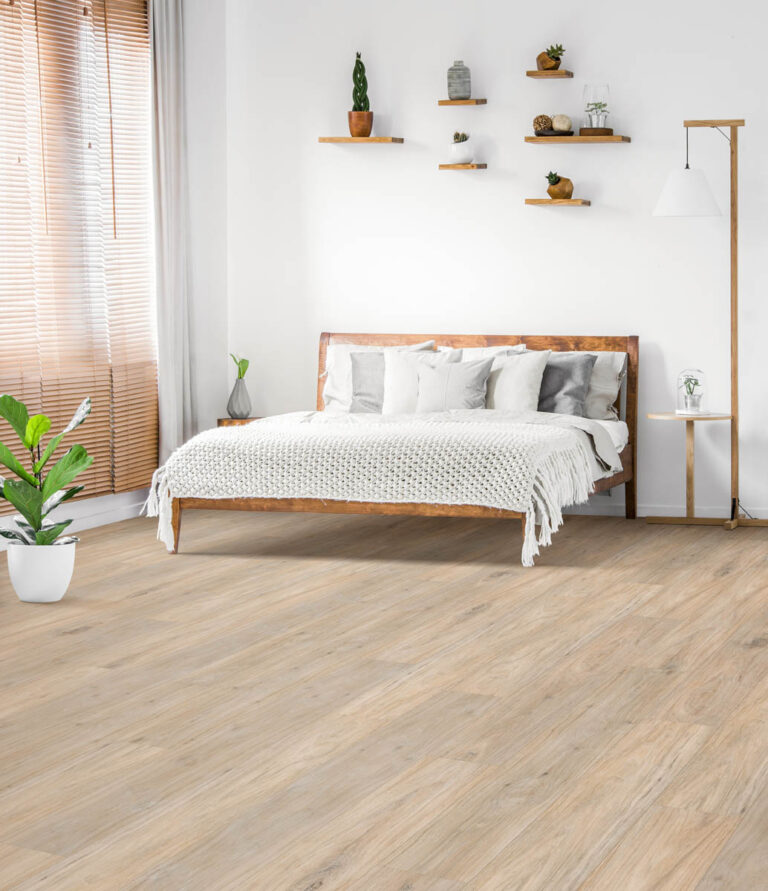 Flooring Installation 18 Minimalist bedroom featuring a wooden bed with white bedding, plants, floating shelves with decor, a floor lamp, and natural light streaming through wooden blinds. The floor is light wood.