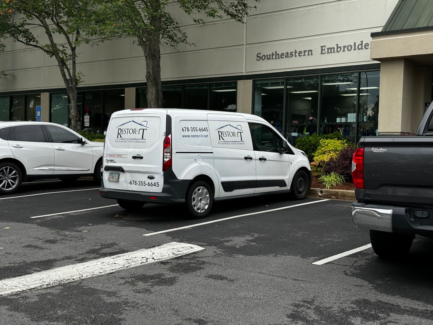 Mold Remediation Services 18 A white van with the "Restore-It" logo and contact information is parked in front of their Marietta office location. About it, other vehicles are also visible.