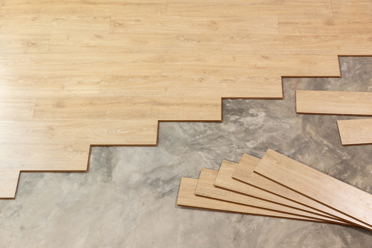 Vinyl Vs Laminate Flooring: Which Is Best For Your Georgia Home? 16 Partially installed wooden floor panels grace the concrete surface of this Georgia home, with additional panels neatly arranged and ready for completion.