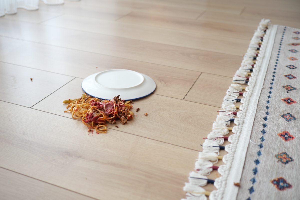 Vinyl Vs Laminate Flooring: Which Is Best For Your Georgia Home? 13 Spaghetti spilled from an overturned plate onto a wooden floor in a charming Georgia home next to a patterned rug.