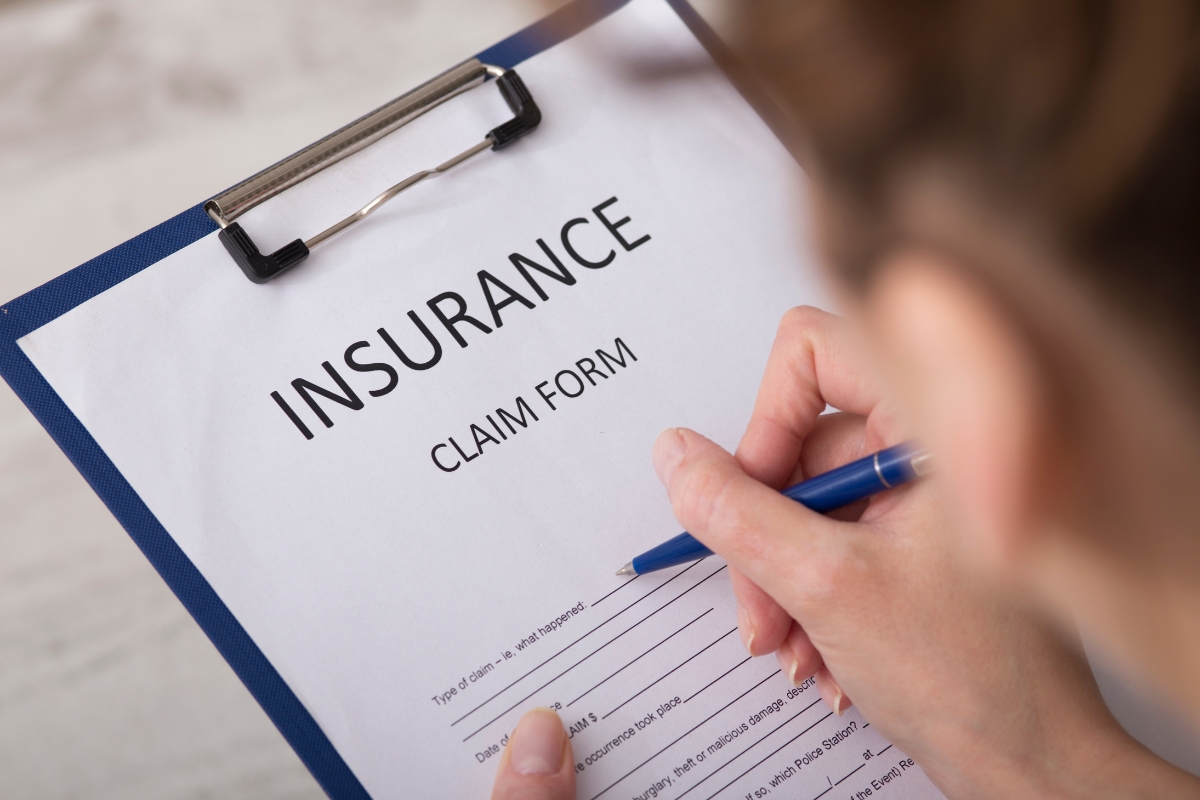 Fire Damage Restoration: Transform Your Home Back To Normal Swiftly 8 A person filling out an insurance claim form on a clipboard with a pen, documenting details for Fire Damage Restoration.