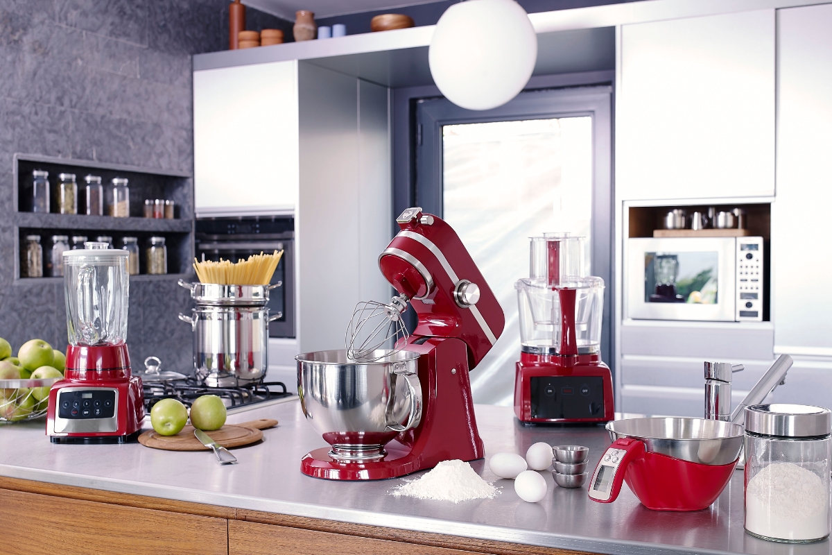 Kitchen Remodeling In Atlanta: How To Transform Your Space 5 A modern kitchen counter, fresh from a recent kitchen remodeling, displays red appliances including a stand mixer, blender, and food processor, surrounded by baking ingredients and utensils.