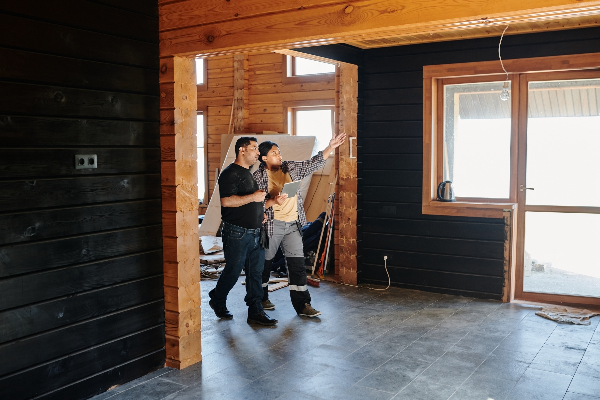 Kitchen Remodeling In Atlanta: How To Transform Your Space 7 Two men stand in an unfinished wooden room, one pointing towards a window, possibly inspecting or discussing kitchen remodeling work.