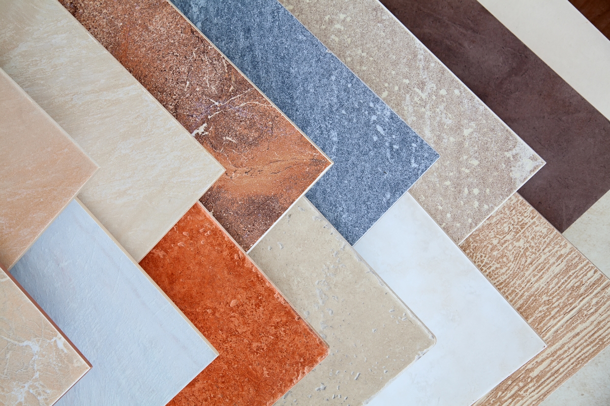 Tile Flooring Installation: Why It’s A Great Choice For Atlanta Homes 19 A variety of rectangular ceramic tiles in different colors and textures are arranged in a diagonal, overlapping pattern, showcasing unique tile flooring installation techniques.