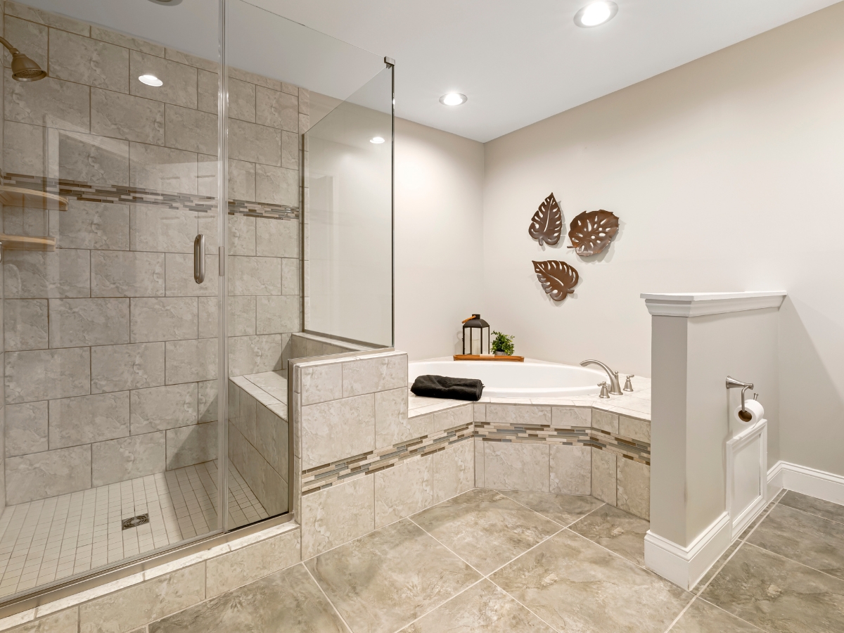 Modern bathroom with a glass-enclosed tiled shower, a corner bathtub, beige tiled floor, and decorative wall art above the tub—showcasing Bathroom Remodeling Trends for 2025.