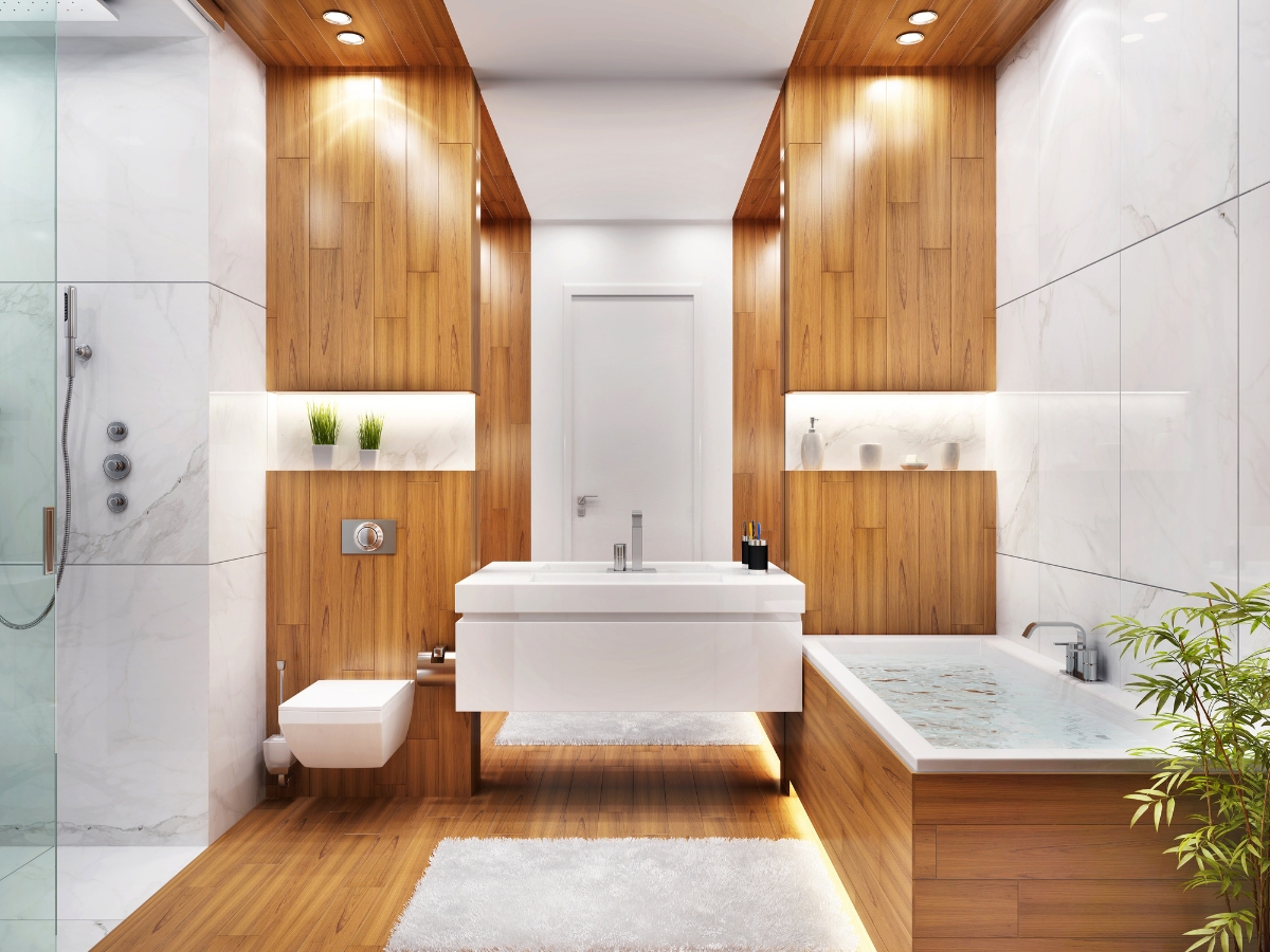 Modern bathroom with wood and marble decor, a floating sink, wall-mounted toilet, bathtub, glass shower, and potted plant; bright lighting and minimalist design reflect Bathroom Remodeling Trends for 2025.