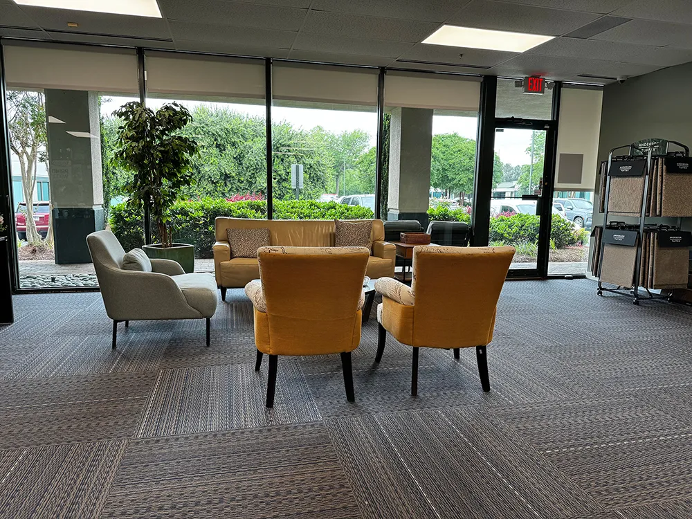 Cozy seating area with yellow and gray chairs, a sofa, and greenery outside.