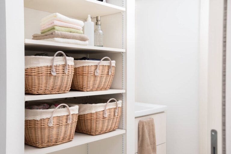 Bathroom And Shower Remodeling 12 Four wicker baskets are neatly arranged on white shelves, with folded towels and toiletries on the top shelf in a well-organized laundry or storage room—an inspiring setting for your next bathroom remodeling project.