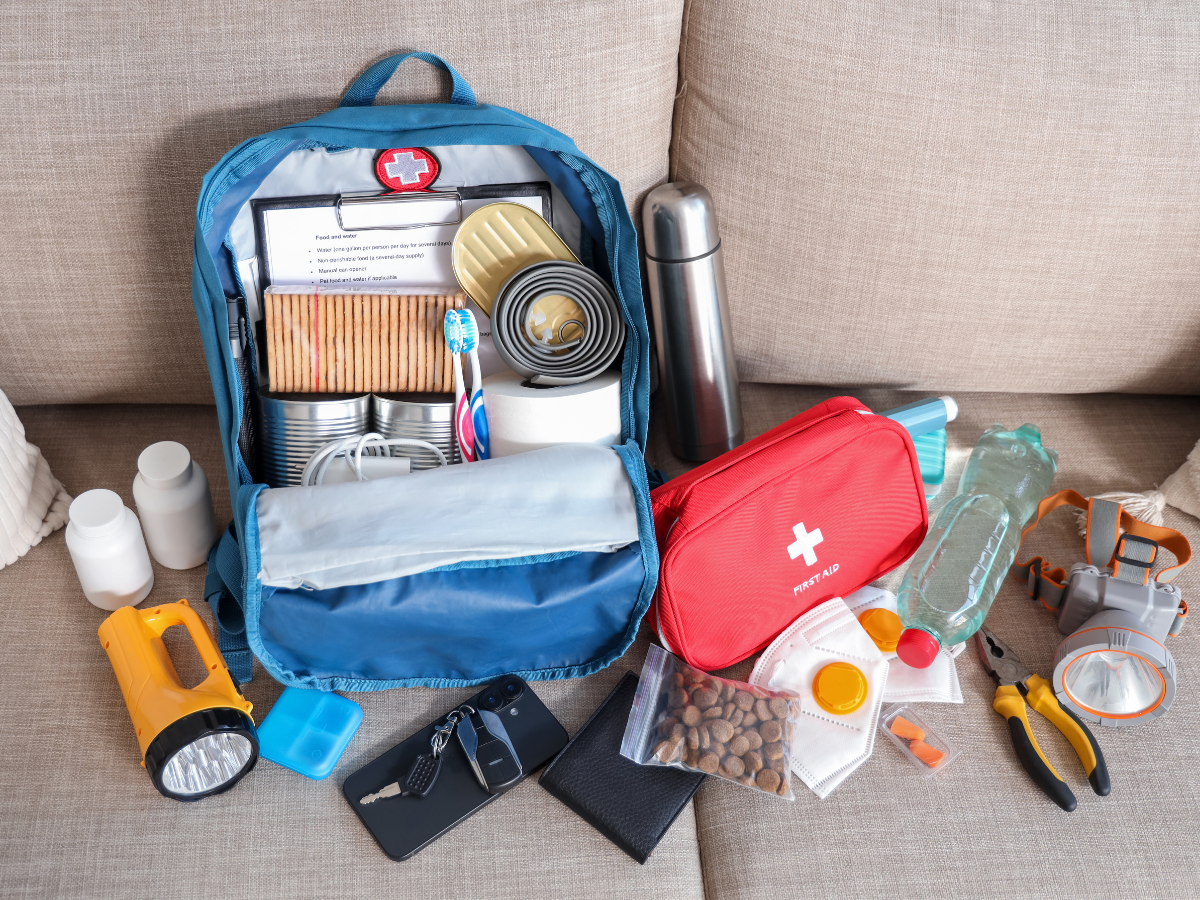 Storm Prep For Atlanta Homes: Emergency Tips And Recovery Strategies 2 An open backpack displays storm prep essentials: canned food, crackers, water bottles, first-aid kit, flashlight, and tools.