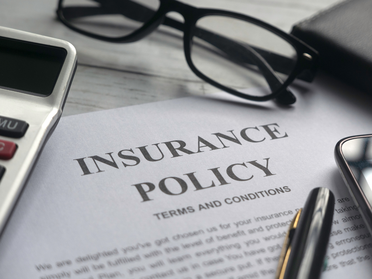 Storm Prep For Atlanta Homes: Emergency Tips And Recovery Strategies 6 A close-up of an insurance policy document surrounded by storm prep essentials—a calculator, eyeglasses, a pen, and a smartphone—arranged neatly on a desk.